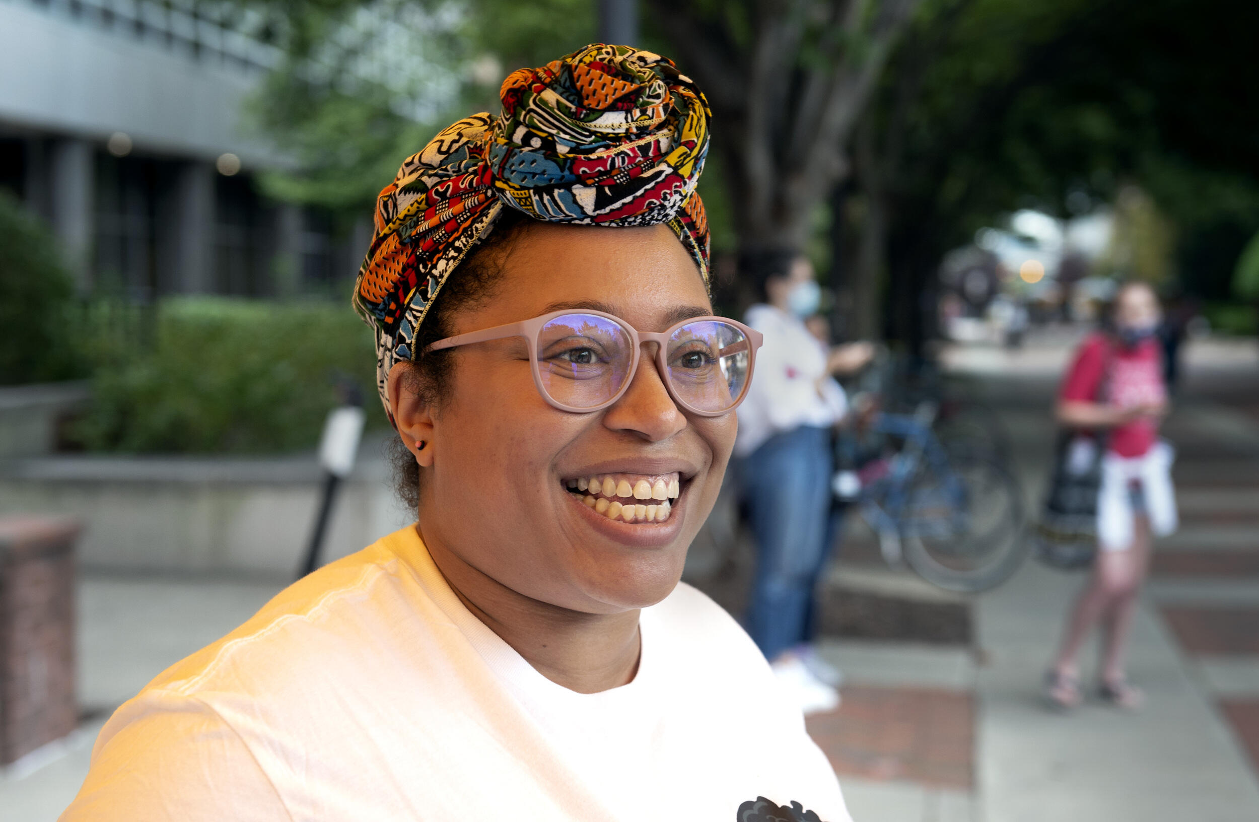 A woman wearing a headscarf and glasses looking to the right 