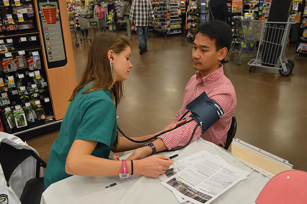 Nursing student Lia Cullen takes pharmacy student Jaeau Obcemea's blood pressure during an Inter Health Professionals Alliance outreach event at the Kroger on Lombardy Street.