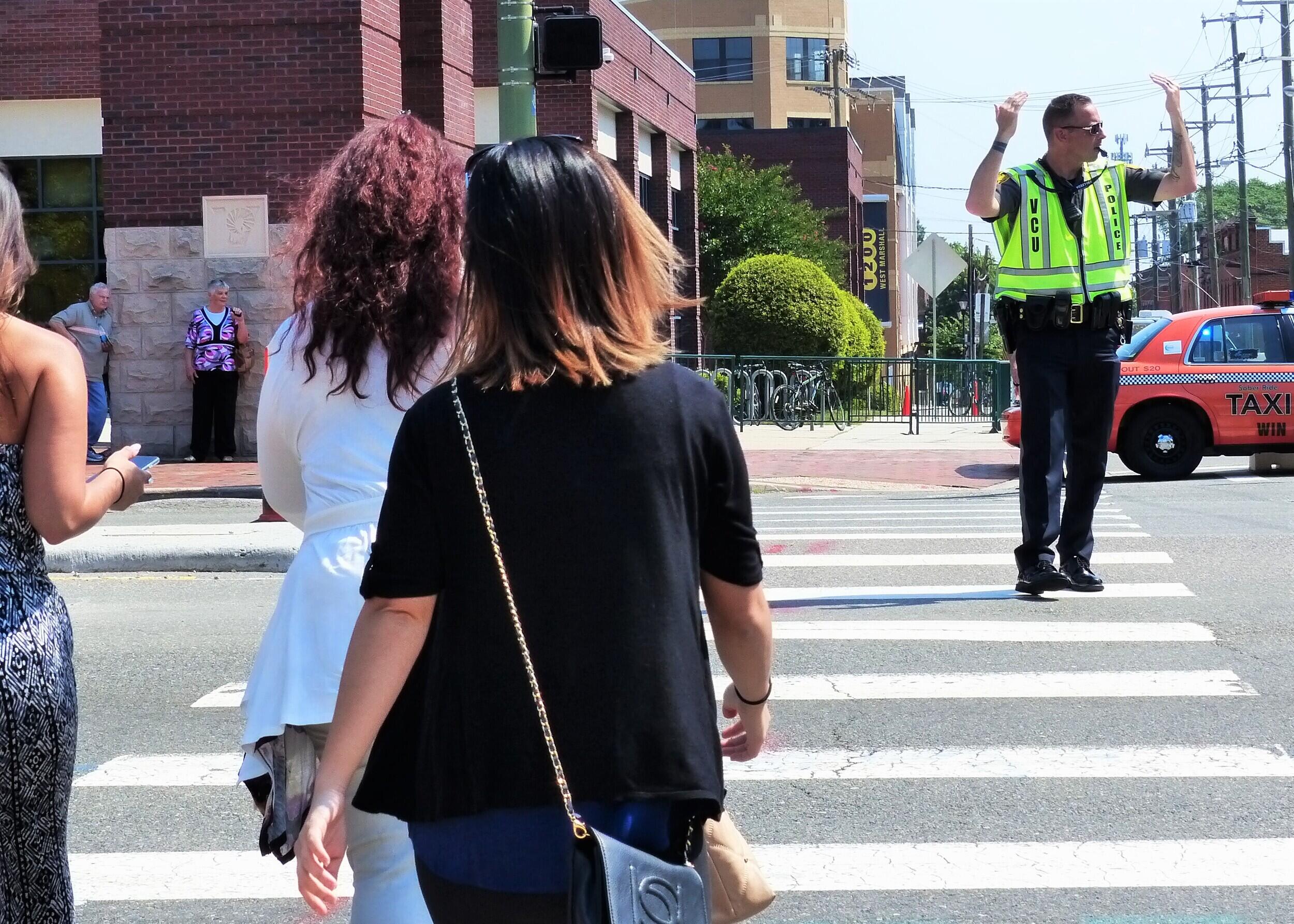 VCU Police Sgt. Bryan Longest directs pedestrians to cross Broad Street during high school graduations in June 2017. (File photo)

