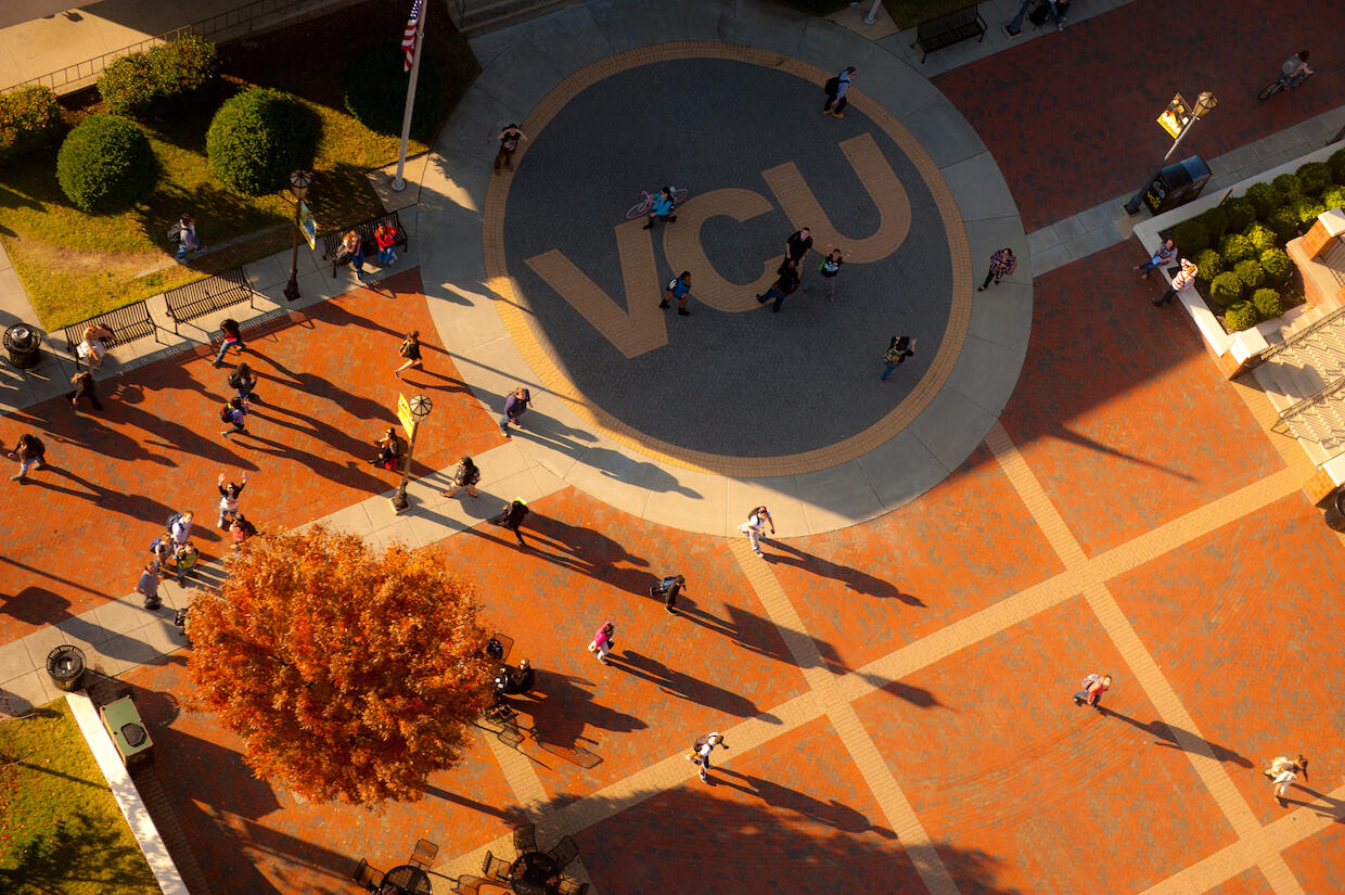 Aerial photo of a courtyard area with a large VCU sign in yellow letters and people walking through.