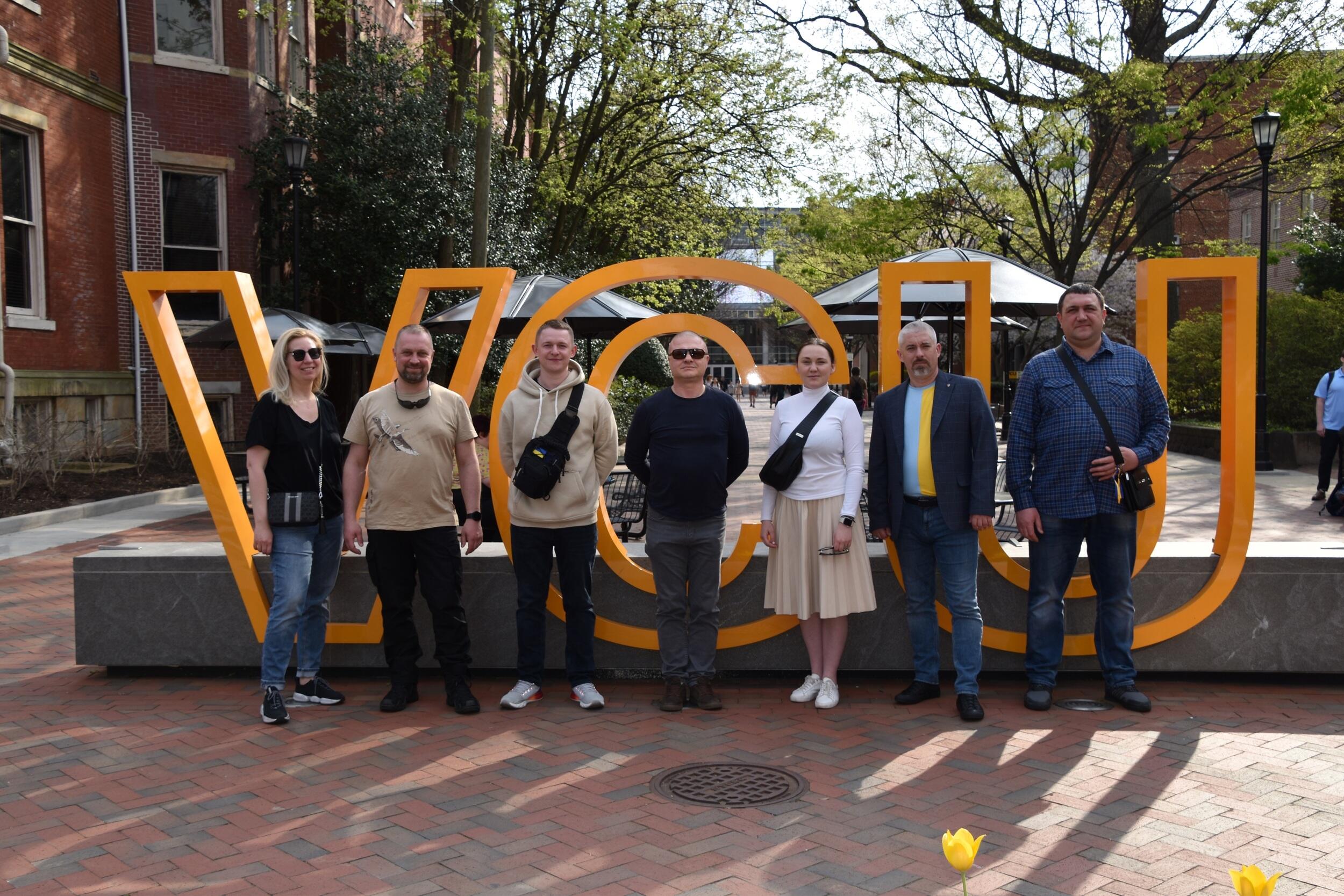 Six people in front of giant yellow letters that spell \"VCU\"