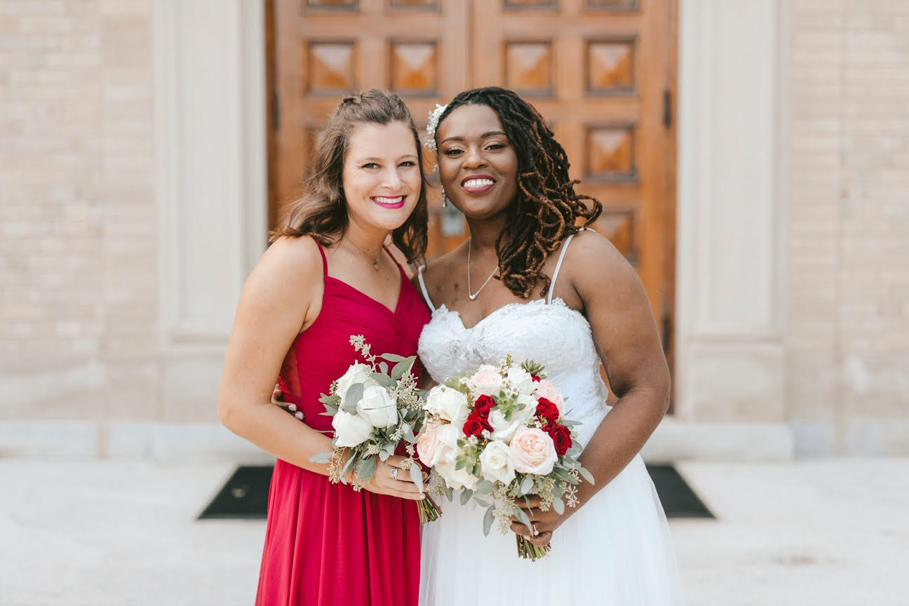 A bride and a bridesmaid standing in front of a church.