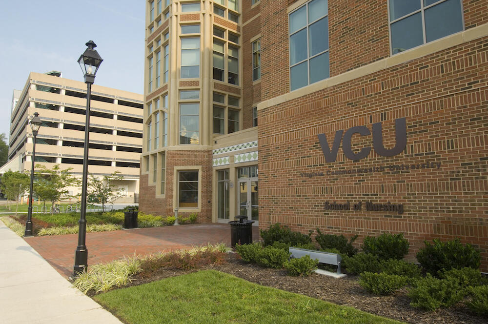 VCU's school of nursing building pictured in foreground with VCU logo and name on side of building facing camera.