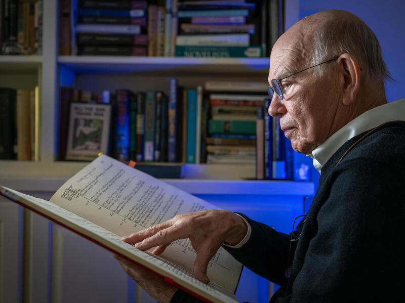 A photo of a man reading a large book. 