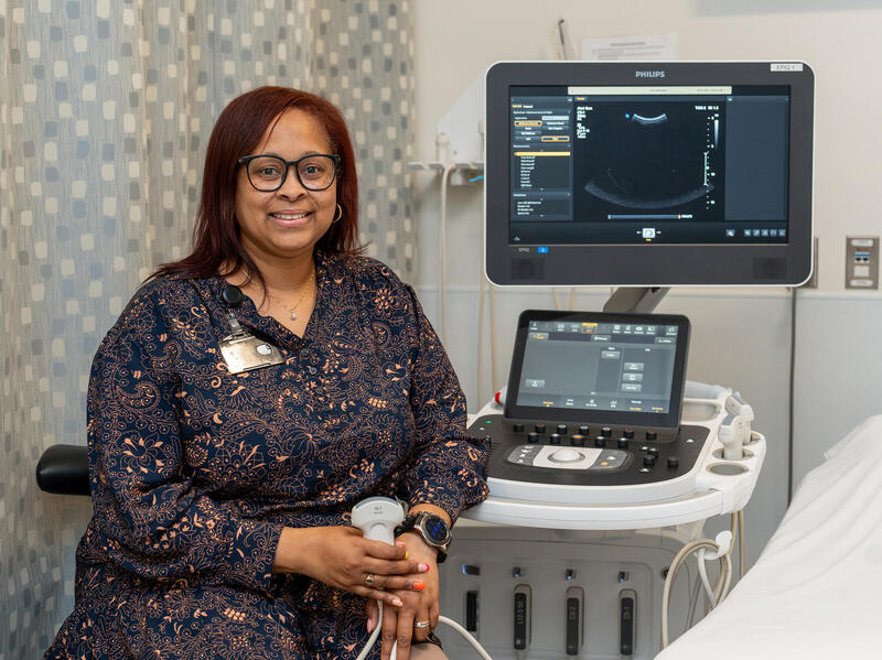 A photo of a woman sitting in front of a sonograph machine.