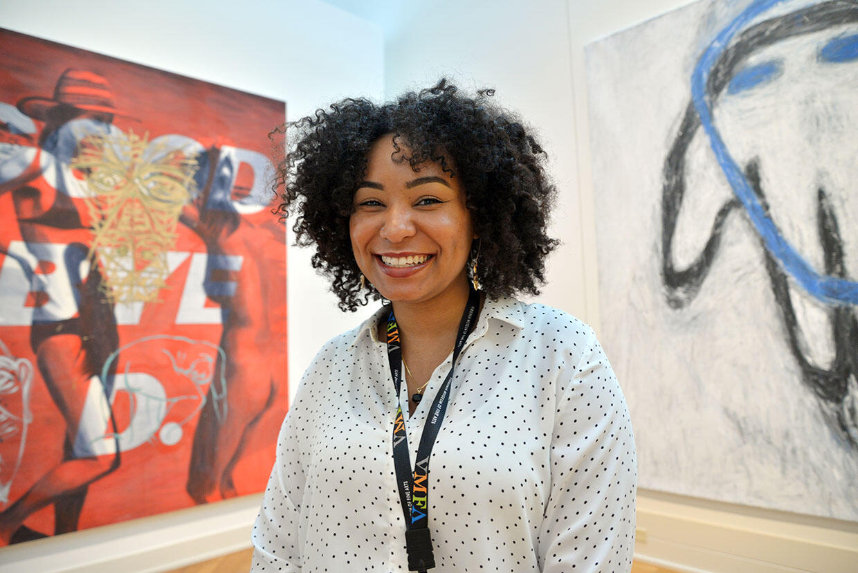 Smiling woman in front of large pieces of artwork.