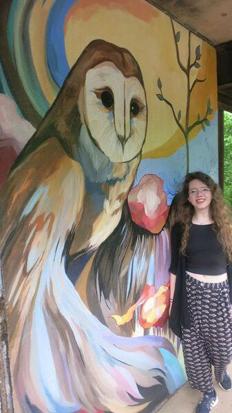 Megan Phillips stands next to her owl mural. Phillips and other students in the VCU School of the Arts painted a series of murals meant to deter graffiti in the James River Parks System. (Photo courtesy of the James River Hikers)