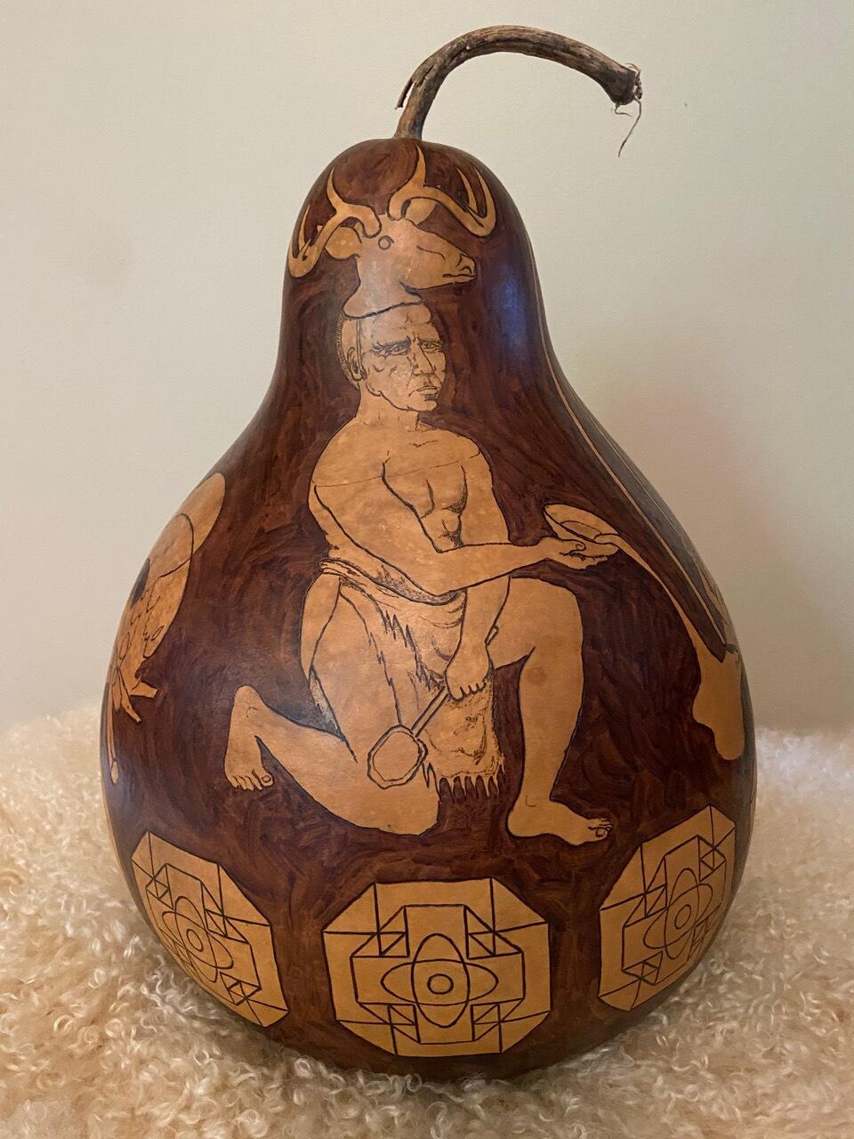 A gourd with an image of a man wearing a deer head on it 