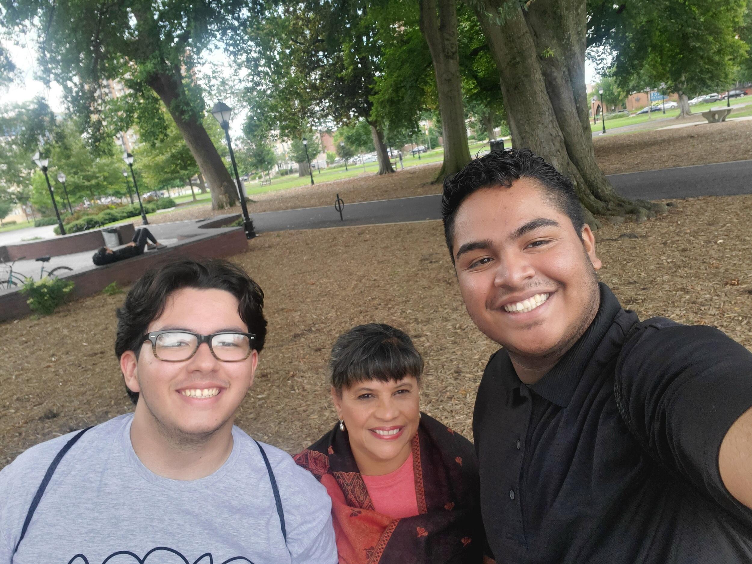 A photo of three people smiling in a park. 