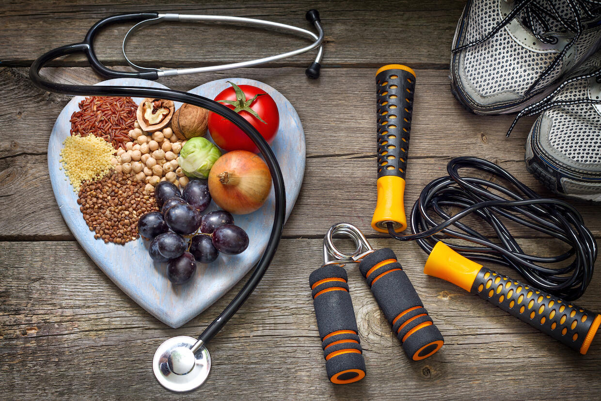 Exercise equipment, a doctor's stethoscope, and a plate with fruits, nuts, and grains.