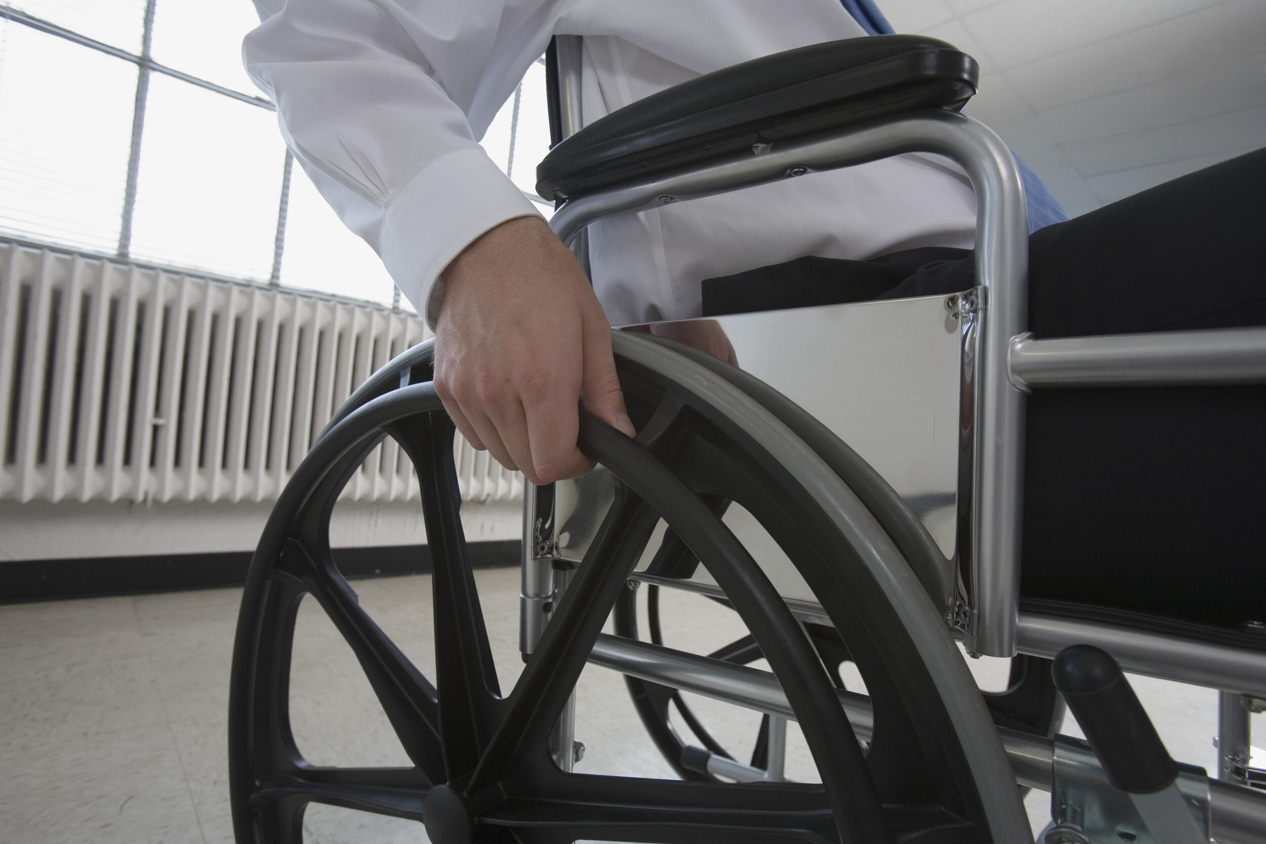 A person seated in a wheelchair grapples a wheel.