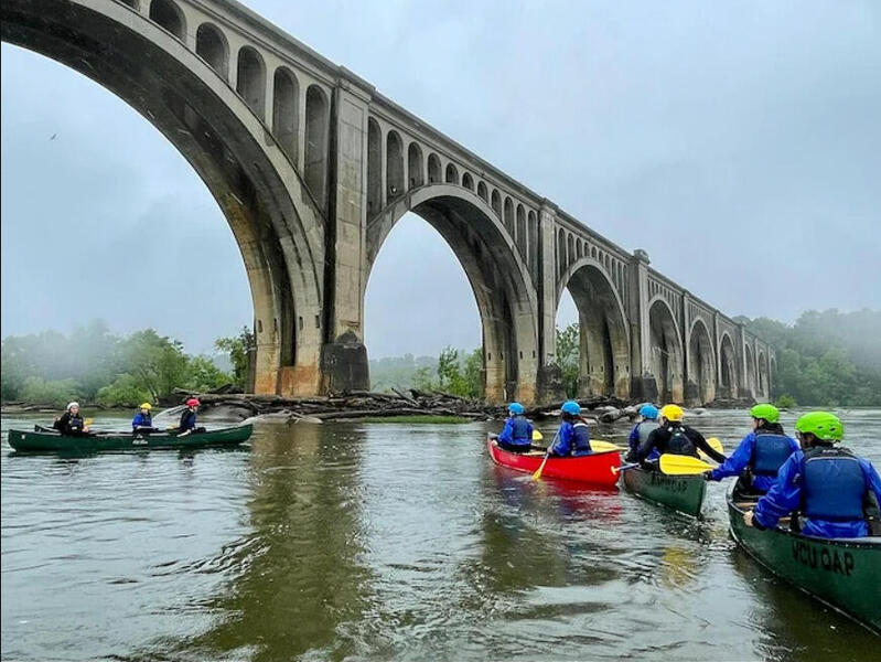 People canoeing on the James River near a bridge 