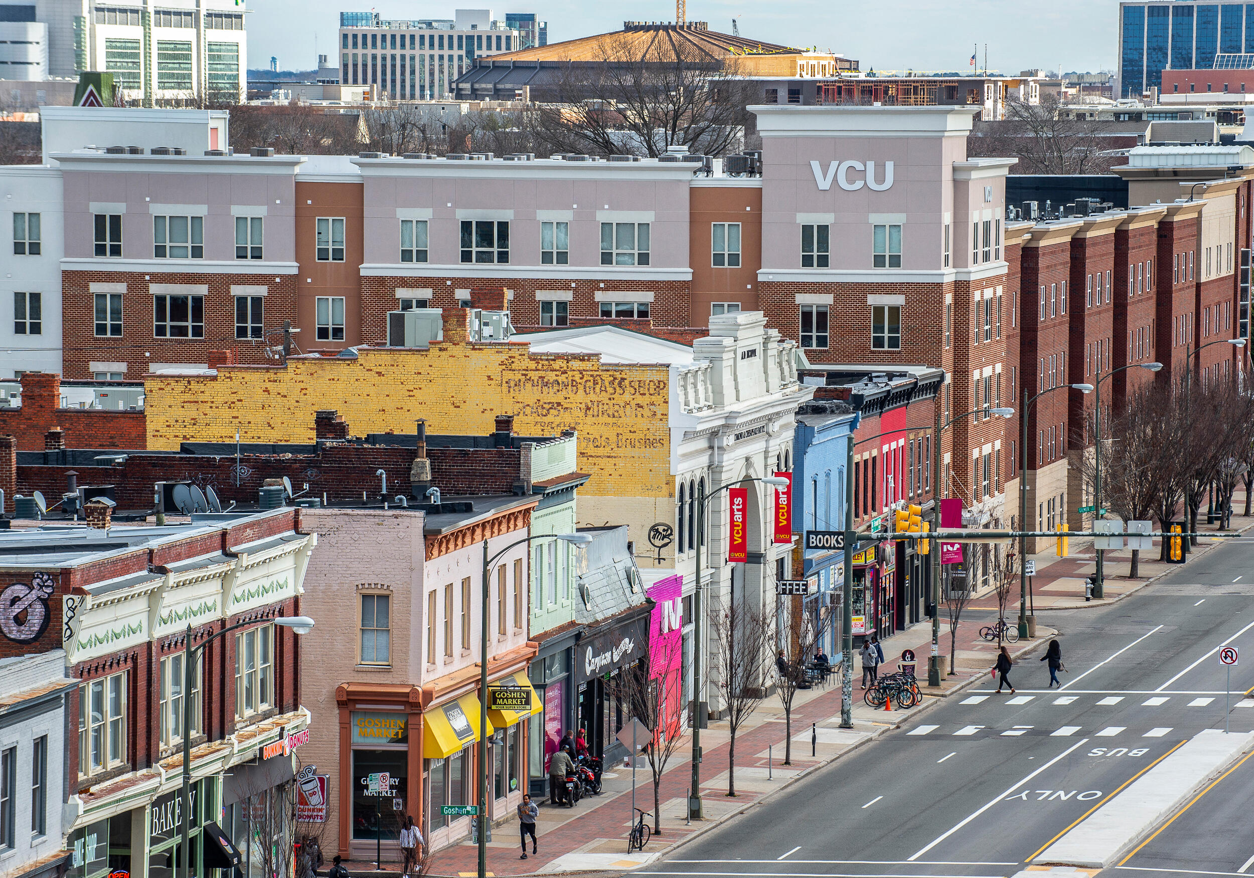 An aerial of a four-lane city street lined with colorful buildings and new apartments, including a VCU building.