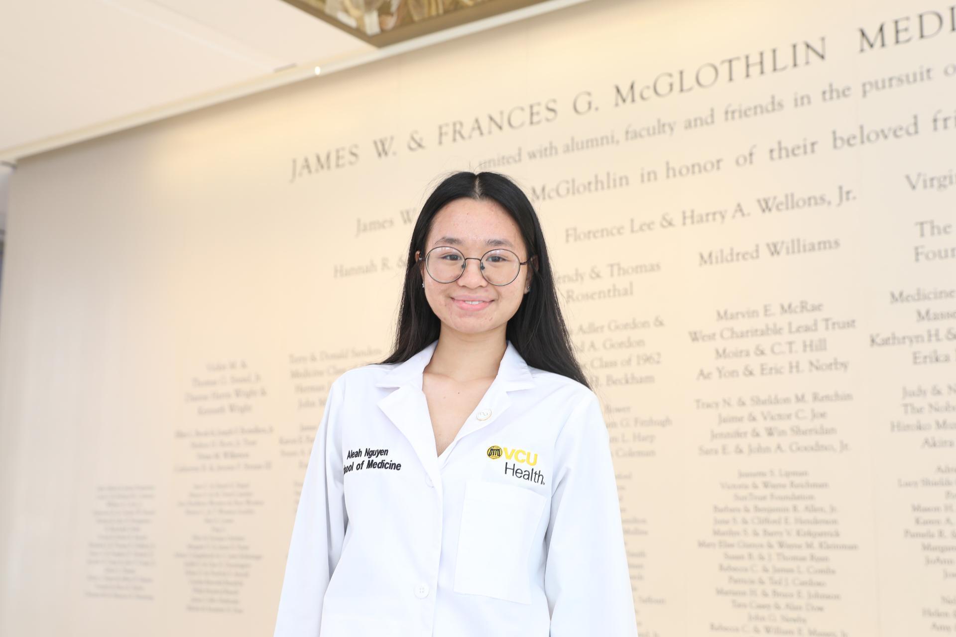 A woman in a white lab coat smiles.