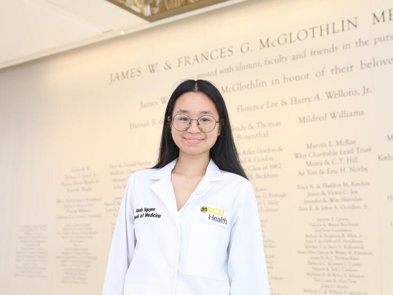 A woman in a white lab coat smiles.