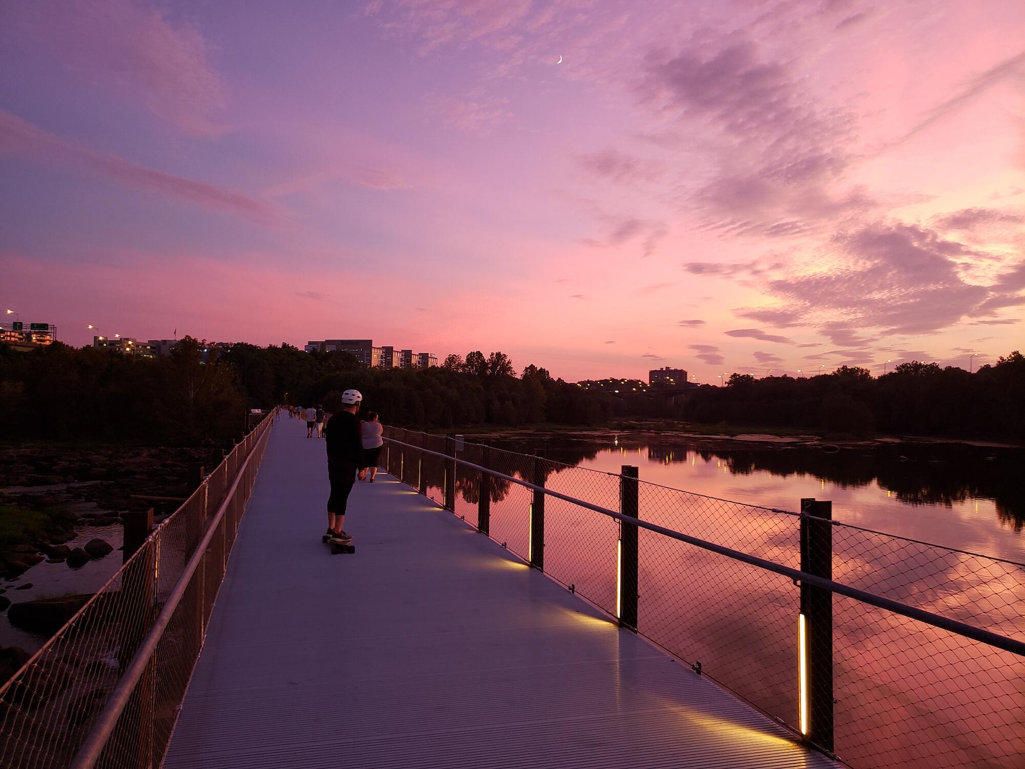 sunset on a pedestrian bridge over a river