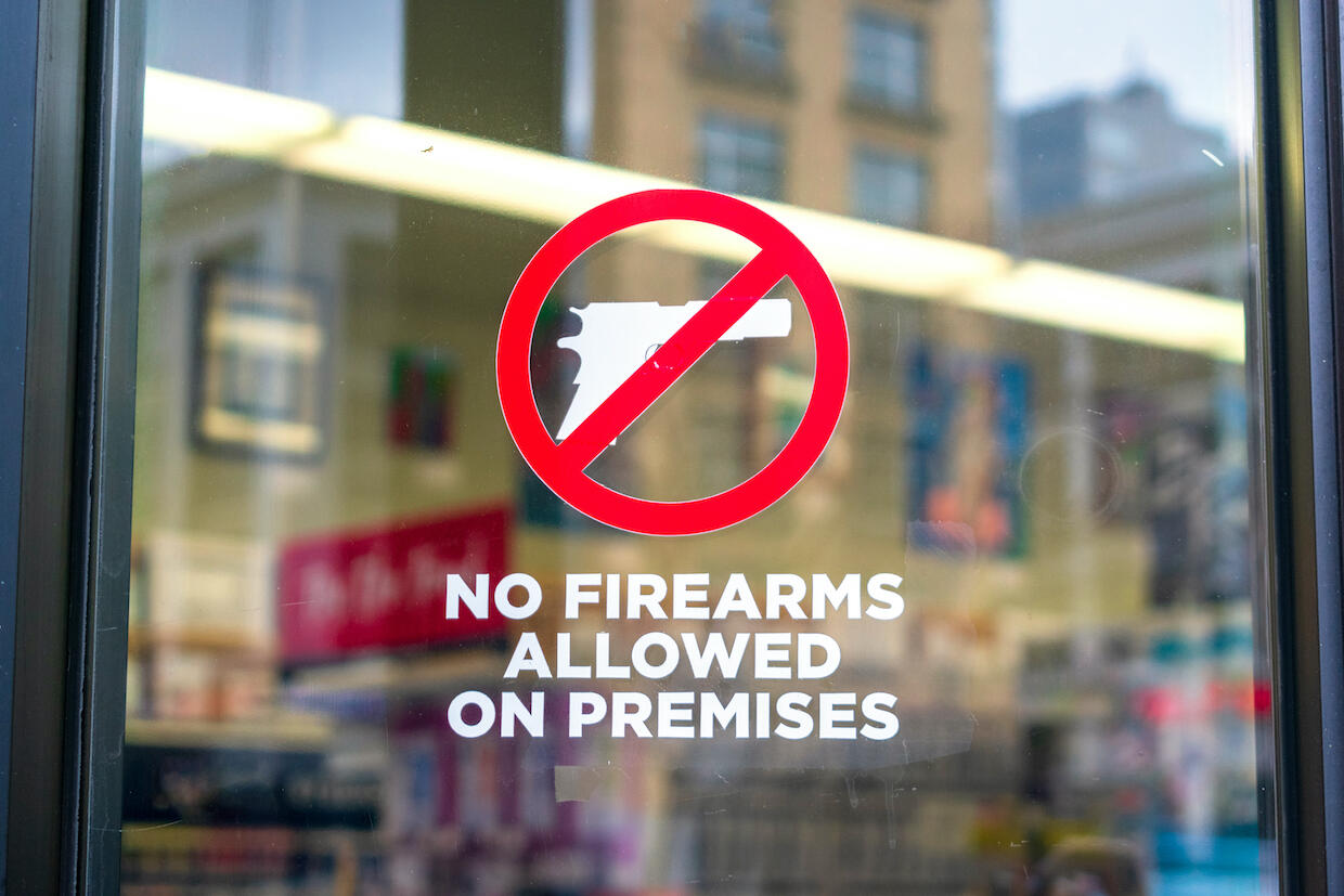 A sign on a window with a gun crossed out. The text below reads \"No firearms allowed on premises.\"
