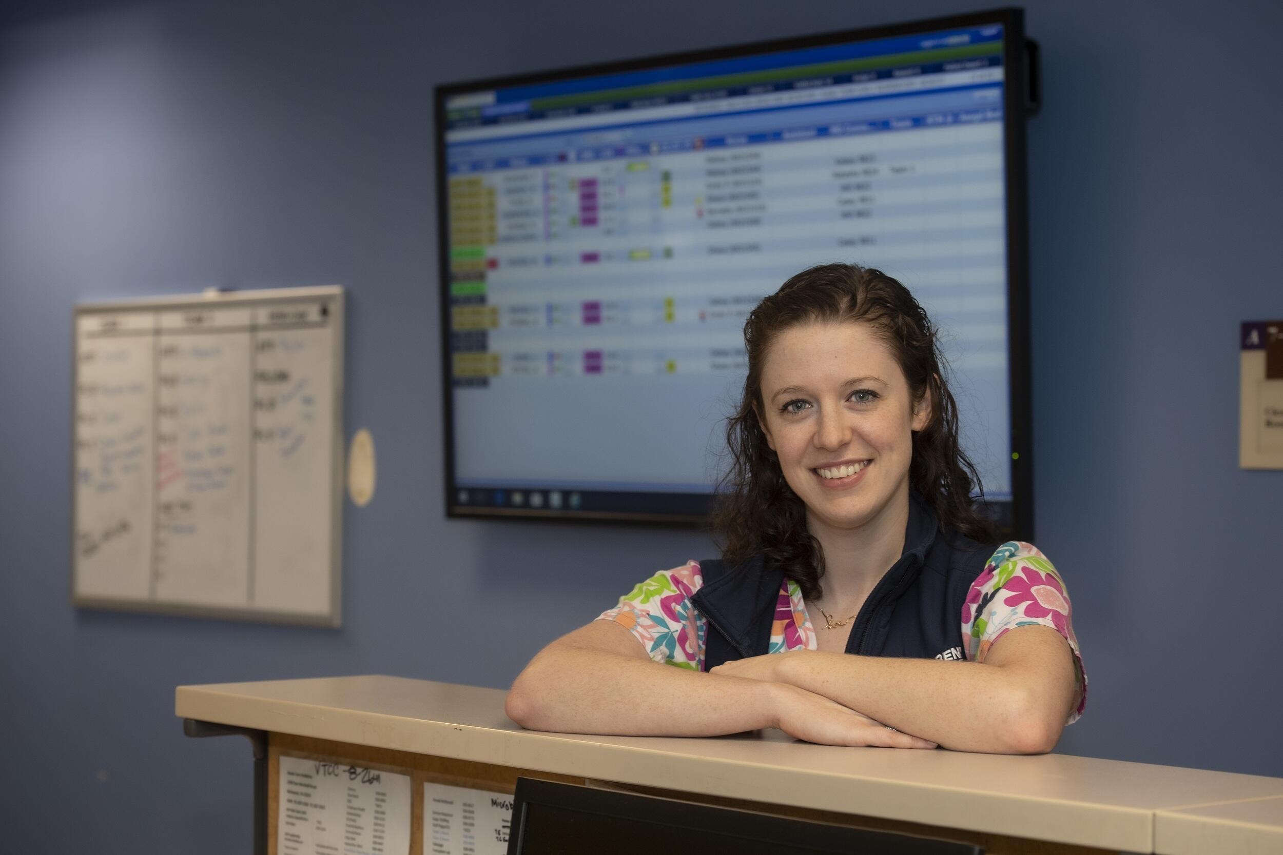 Jenn Brigle standing behind a nurse's station desk.