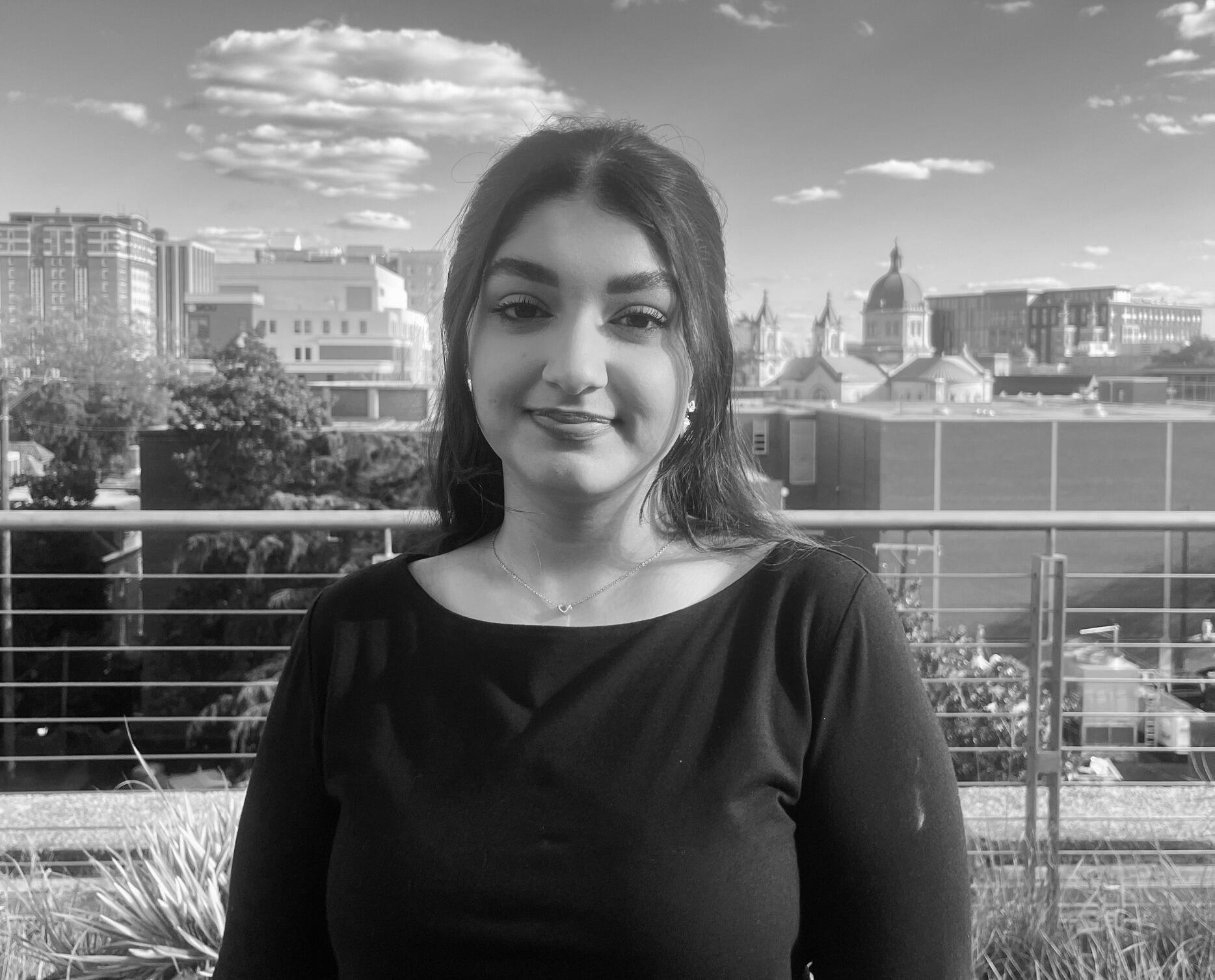 A photo of a woman standing in front of a city skyline. 