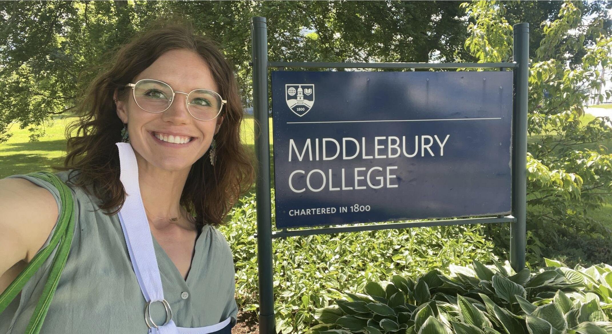 Madeline Doane standing next to a sign that says \"Middlebury College.\"