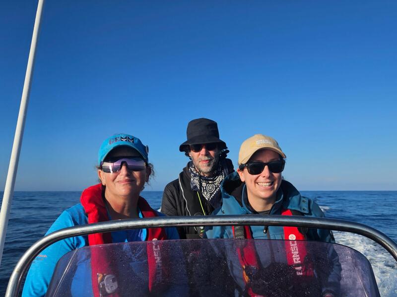 A photo of three people standing on a boat. 