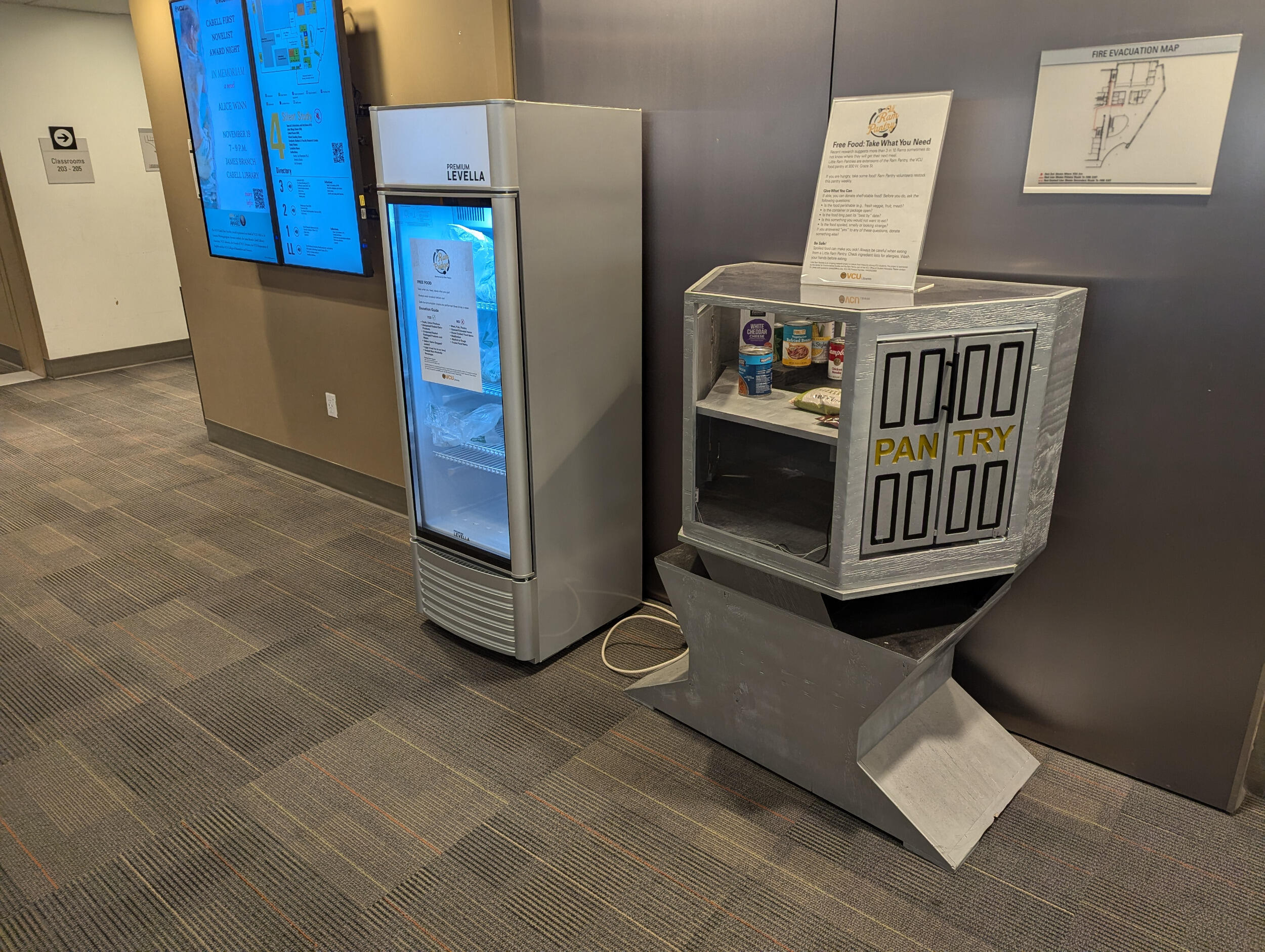 A small refrigerator sits against a wall alongside a small pantry with food in it.