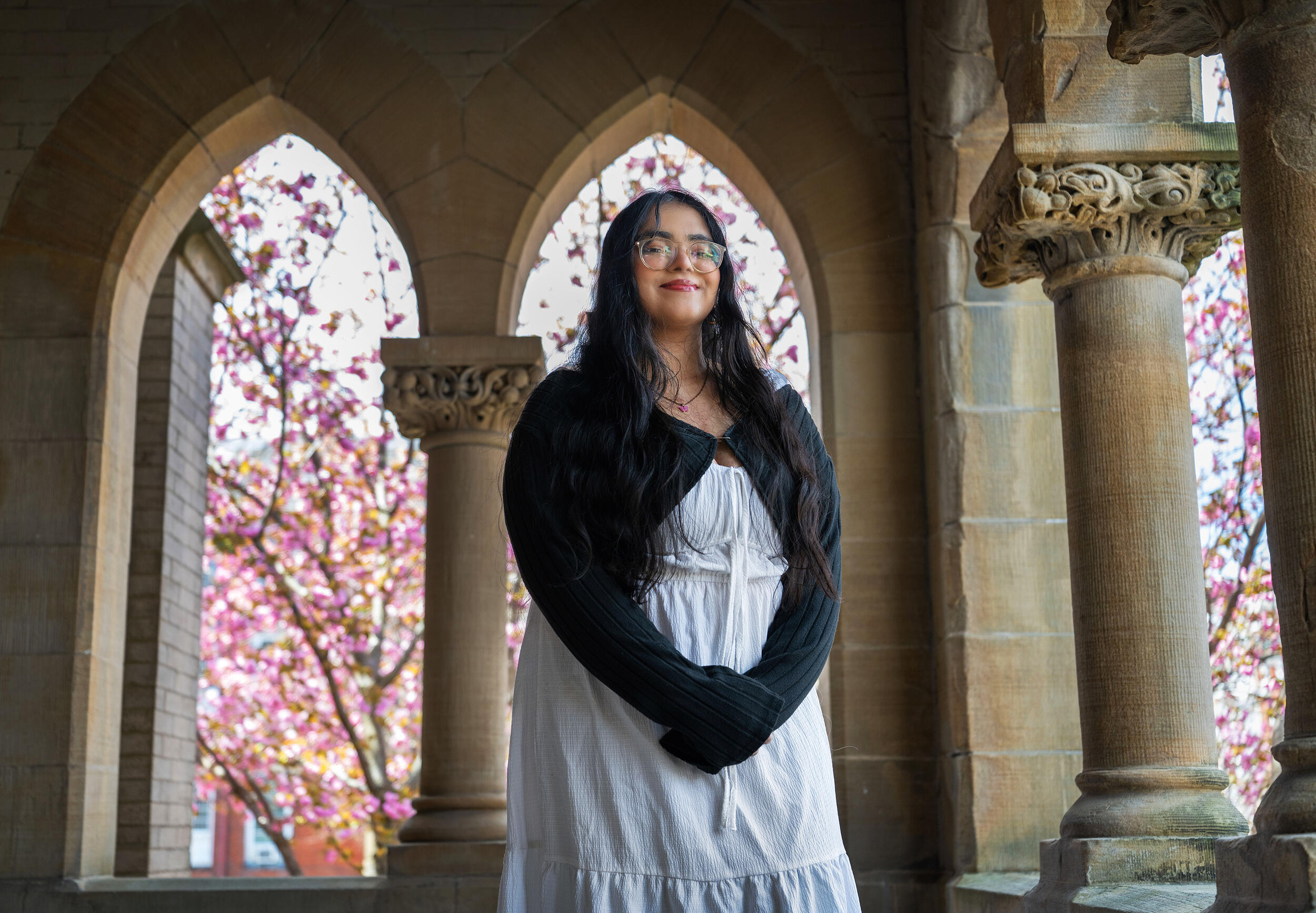 A photo of a woman standing in front of an archway. 