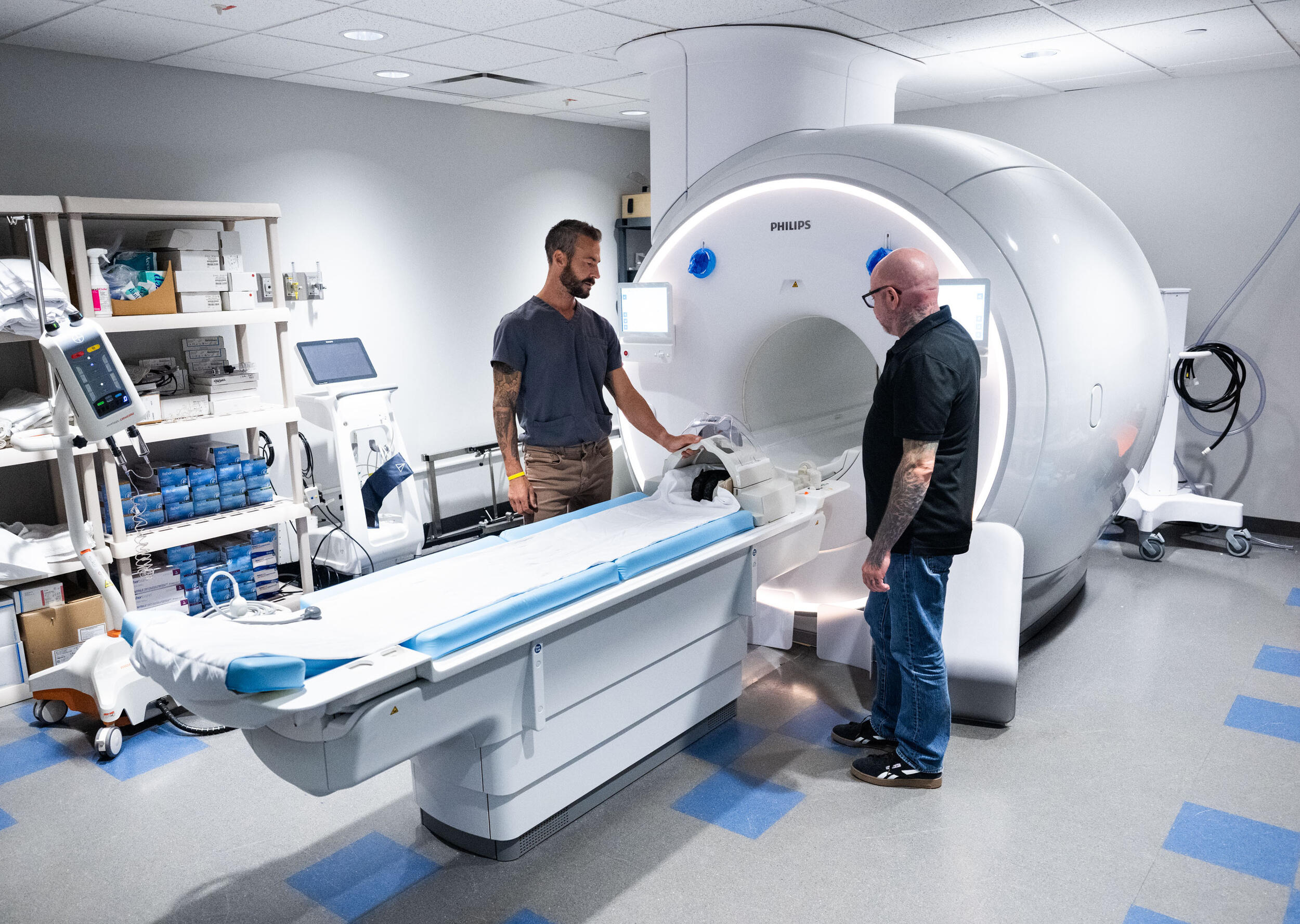 A photo of two men standing in front of an MRI machine. 
