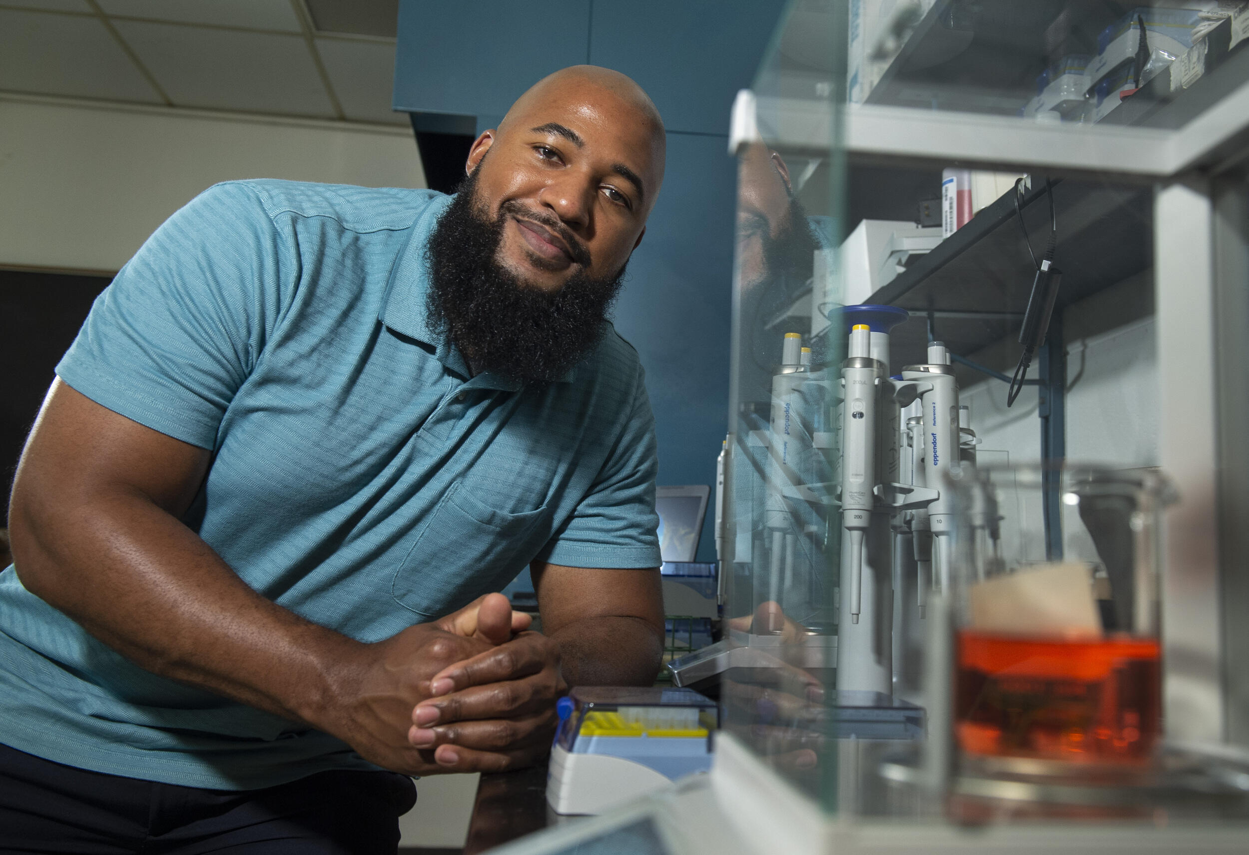 Mychal Smith, Ph.D., an assistant professor in the VCU Department of Chemistry, leans on a counter in a lab.