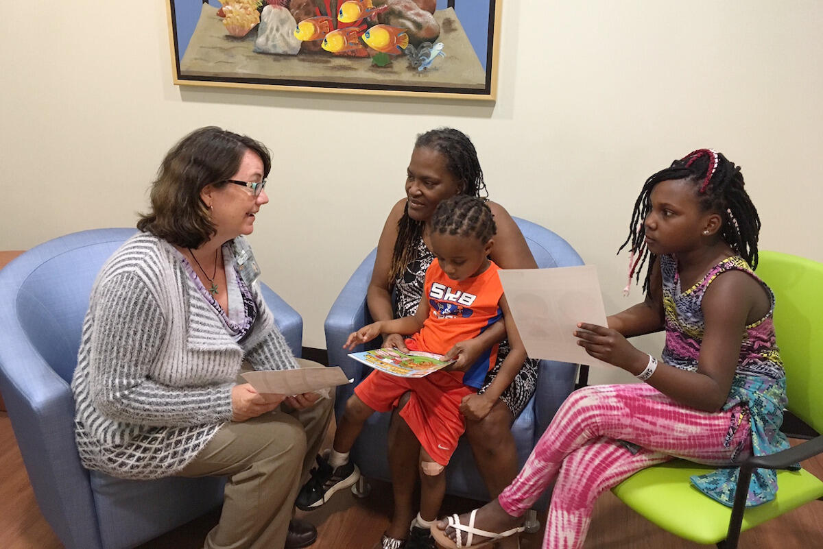 Zorater Miles with grandchildren Christian, center, and Iyanna, right, speaks with Kathleen Bowden, MSW, social worker for the UCAN community asthma program. <br>Photo by Kate Marino