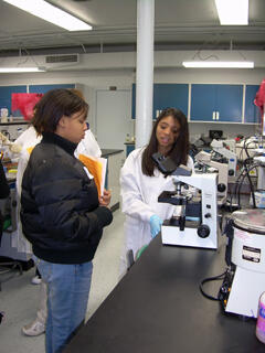 Jenica Patel, a junior in clinical laboratory science program, shows Girls Scouts different types of leukemia cells through a microscope. Photo by Anna Goroncy