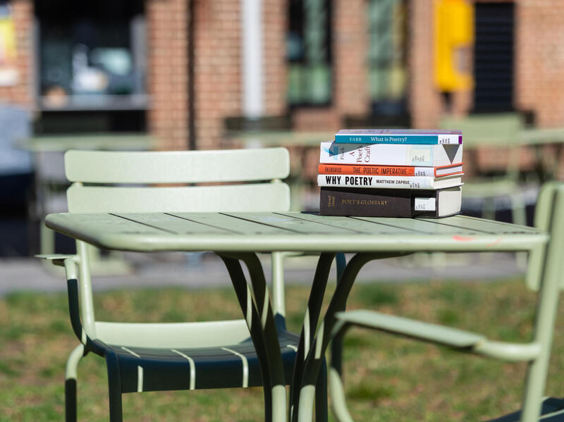 Table with stack of books with titles like Why Poetry and The Poetry Imperative.