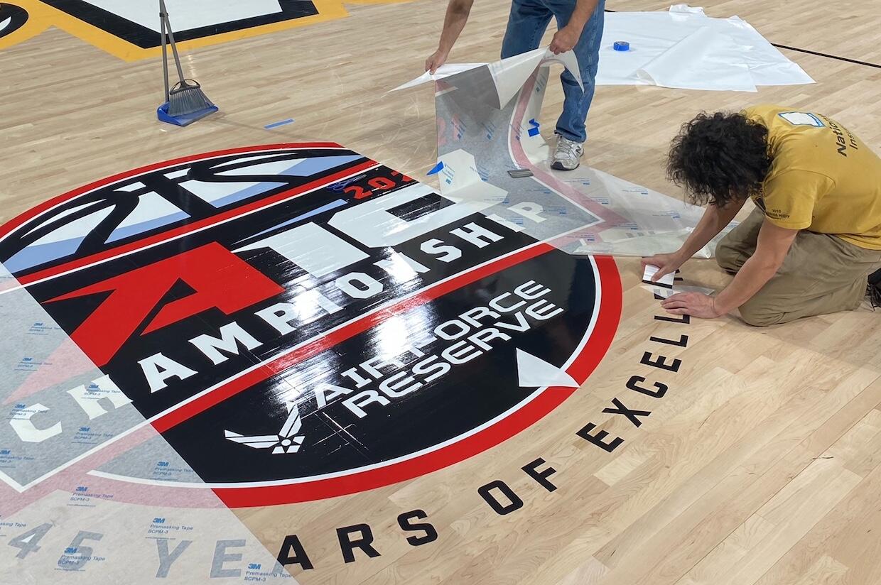 Workers lay down decals on the floor at the Stuart C. Siegel Center.