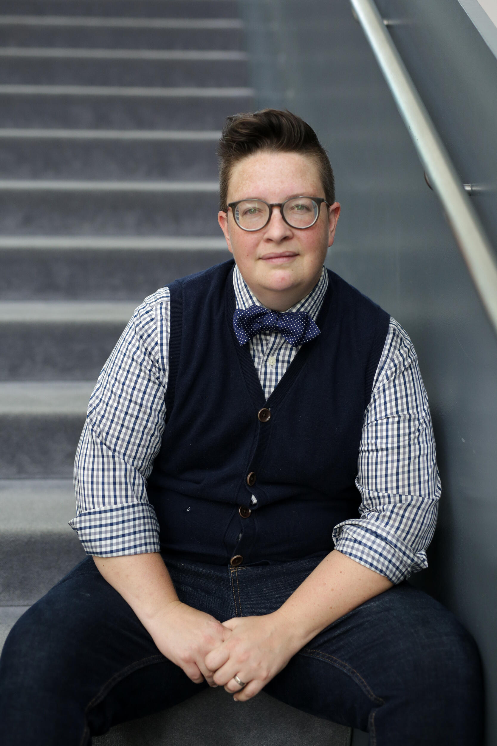 Person sitting on staircase wearing dark vest and bowtie.