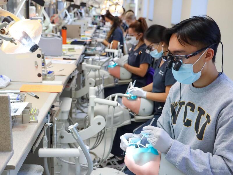 A photo of a row of dental students working on practice dummy heads