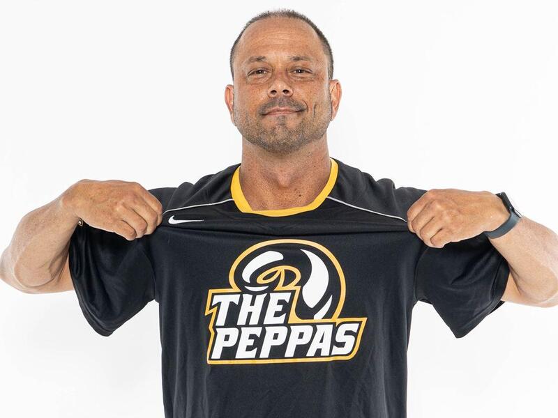 A man holding a jersey up to his chest that reads \"The Peppas\" 