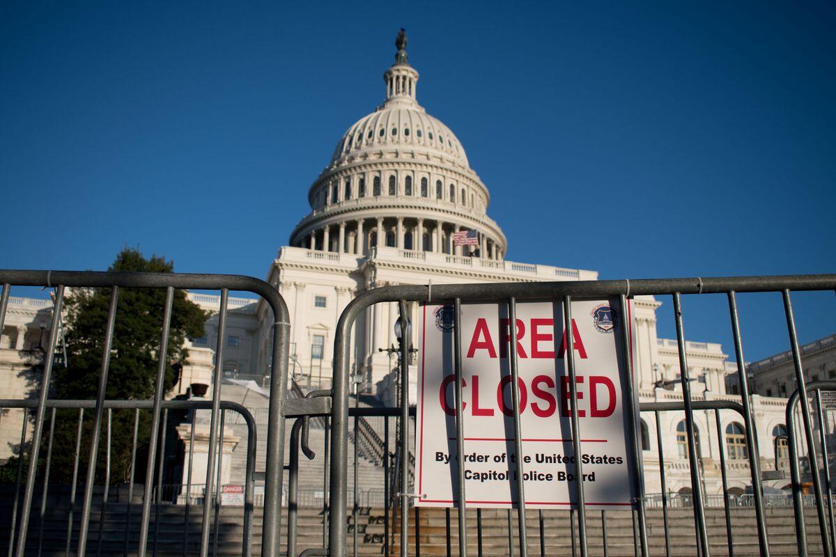 A photo of a gate in front of the U.S. Capitol with a sign that says \"A R E A C L O S E D\" in red letters. 
