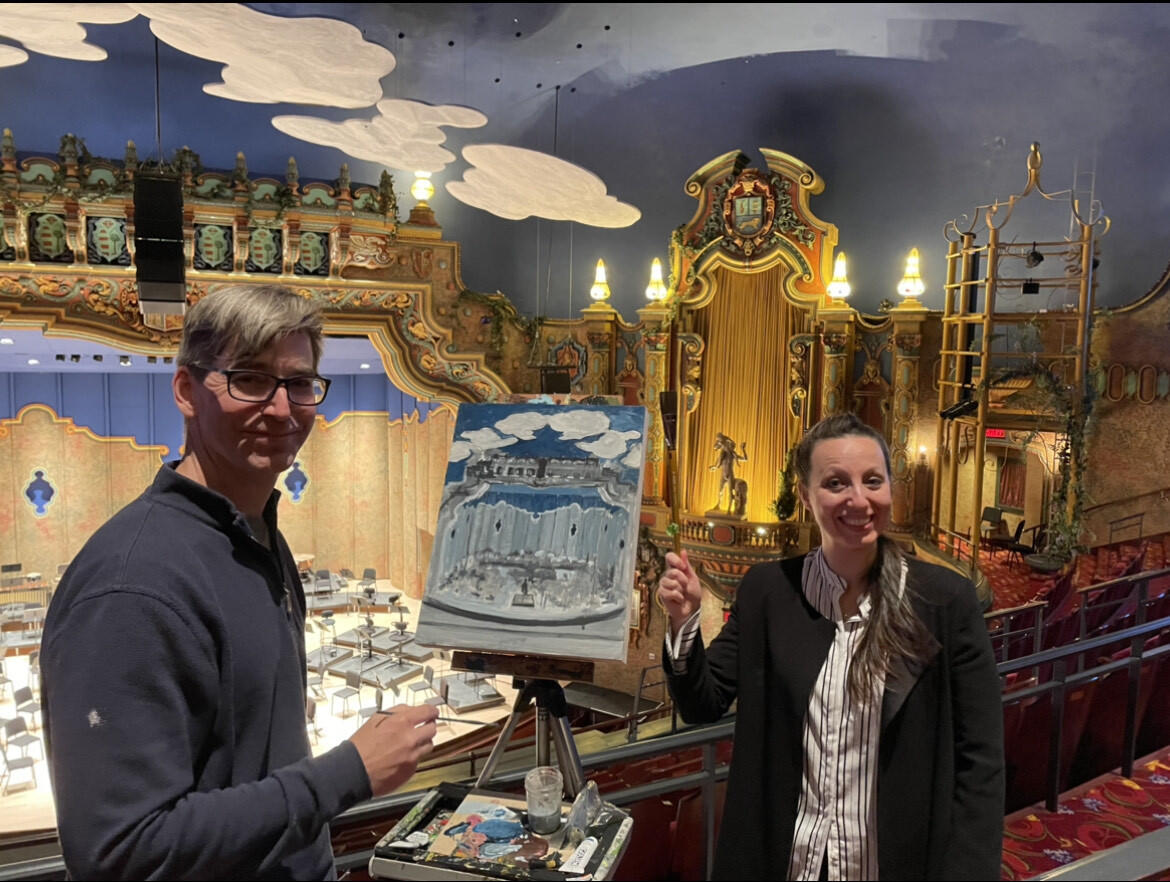(Left to right) Matt Lively with Valentina Peleggi, music director of the Richmond Symphony. Lively is holding a paintbrush and standing in front of a painting 