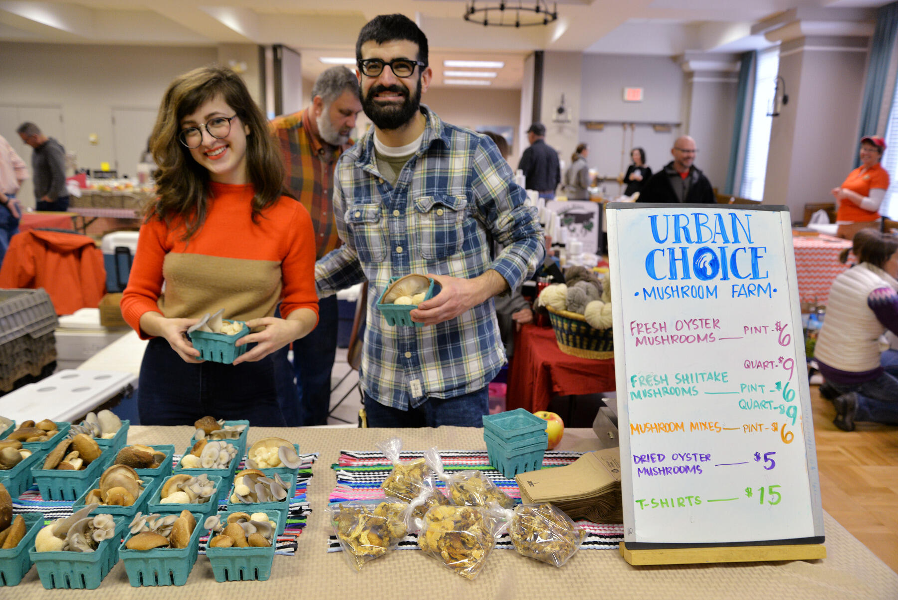 Lindsay Hawk, who graduated from the School of the Arts in May, and Jake Greenbaum, who graduated in 2015 from the School of Business, sell mushrooms for Urban Choice Mushroom Farm at a local farmers market.
<br>Photo by Brian McNeill, University Public Affairs.