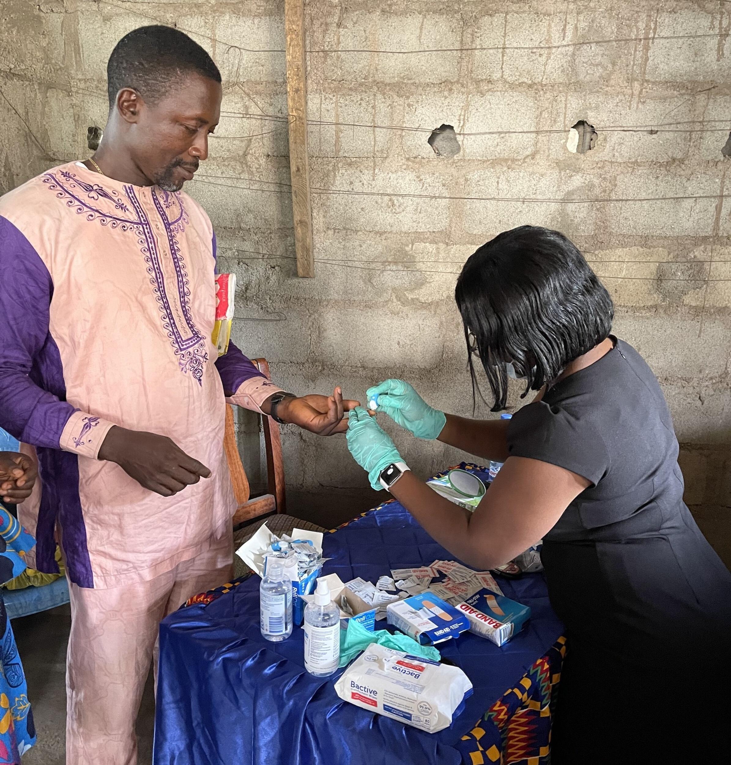 Pharmacy student Blessing Tomlah, right, gives free glucose tests to residents of her former hometown of Limbe, a rural agricultural community in Cameroon, during summer 2021.