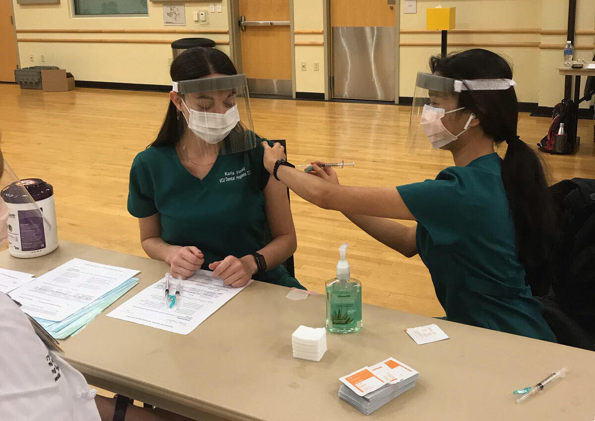A student demonstrating how to administer a vaccine on a classmate.