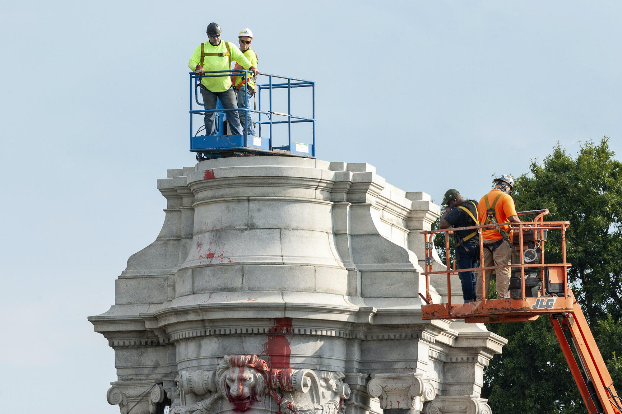 Workers atop the empty pedestal after the Robert E. Lee statue is removed