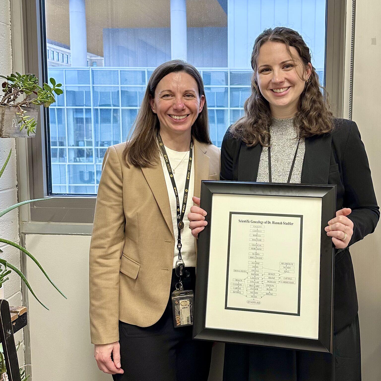 A photo of two women standing next to each other. The woman on the right is holding a photo frame. 