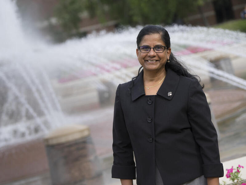 Mangala Subramaniam standing in front of a fountain 