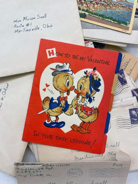 A vintage Valentines card surrounded by envelopes and postcards.