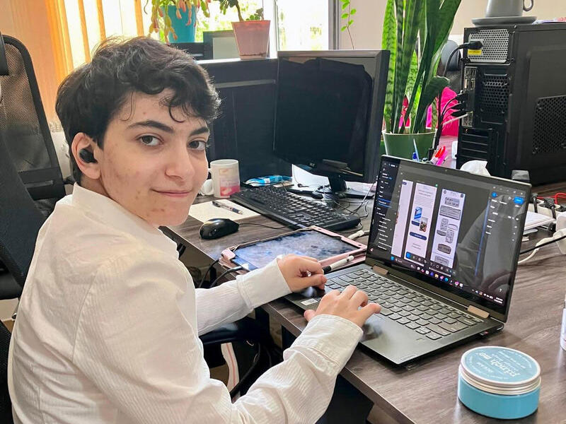 A photo of a man sitting at a table with a laptop. 