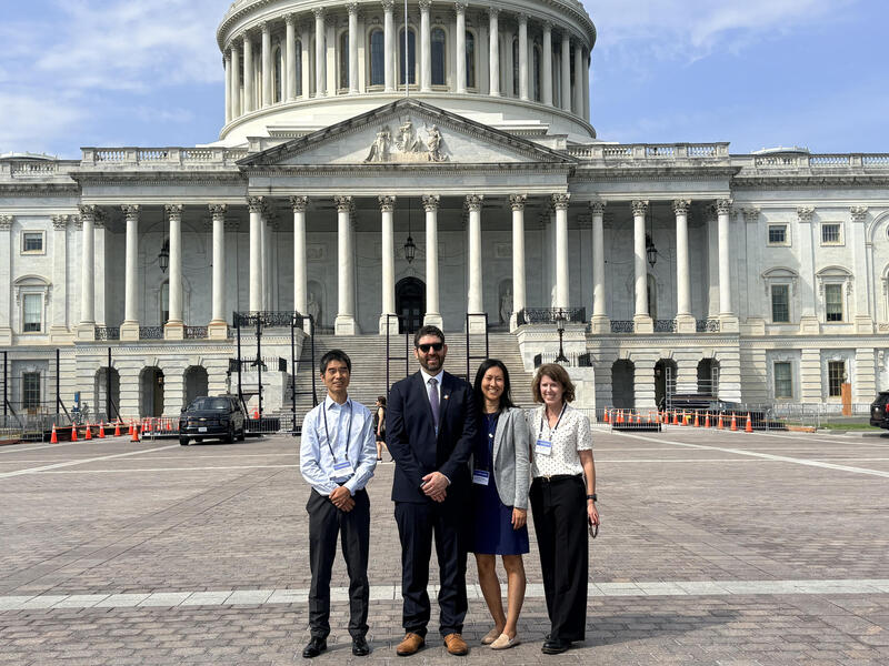 A photo of four people standing in front of the U.S. Capitol building. 
