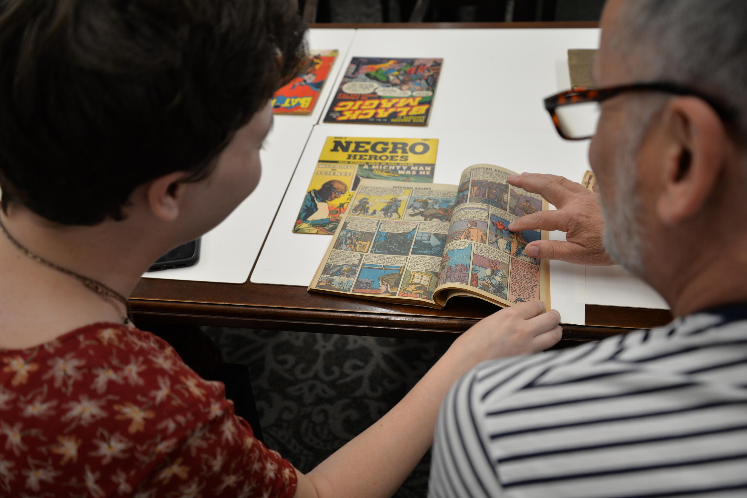 Two people reading a comic book.