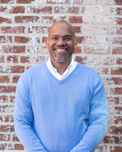 Vann Graves, Ph.D., smiling and standing in front of a brick wall