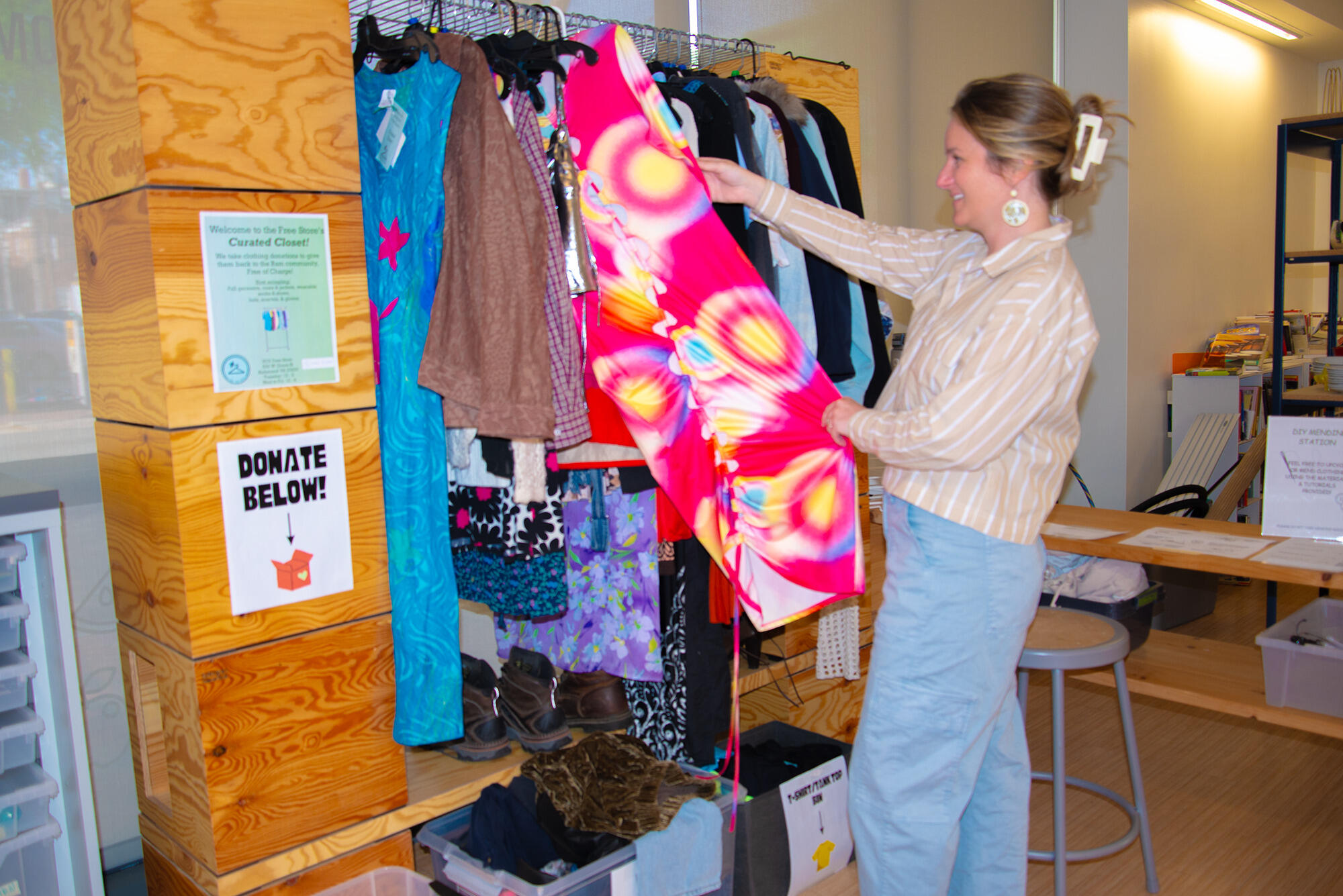 A photo of a woman pulling a dress from a rack and looking at it. 